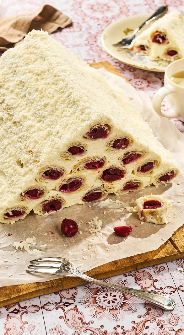 Kuchen-Pyramide mit Kirschen und Kokos auf gemustertem Tischtuch