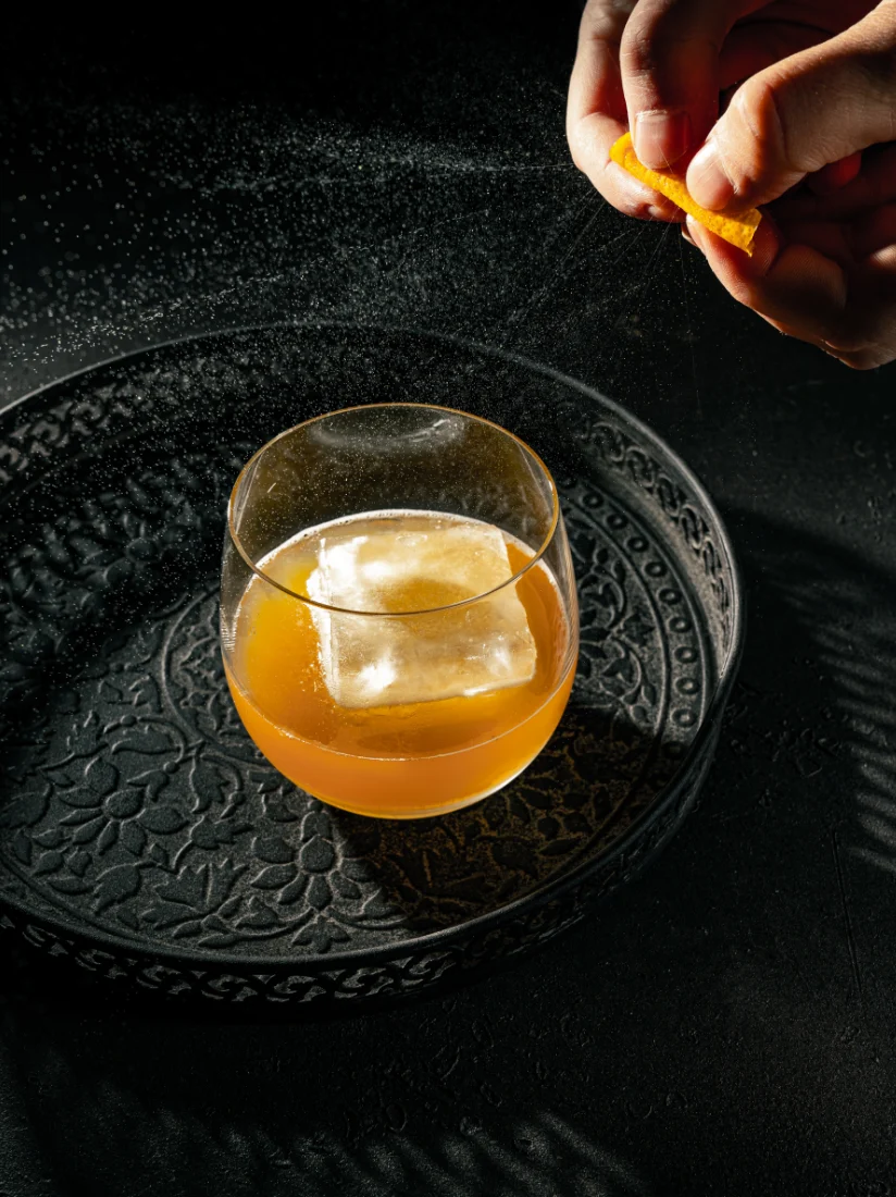 Drink mit Eiskugel, eine Orangenzeste wird darüber abgezogen