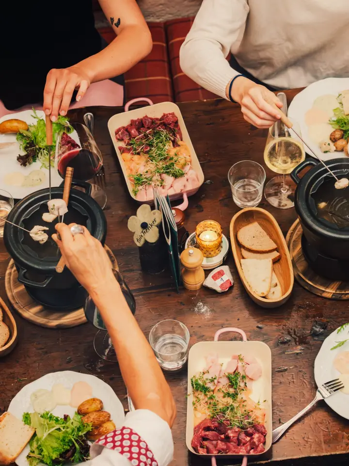 Fondue-Abend mit vielen Händen am Tisch